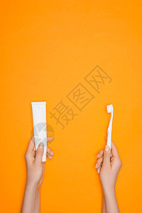 妇女持有牙刷和牙膏管以橙色图片