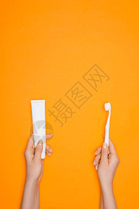 妇女持有牙刷和牙膏管以橙色背景图片