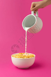 将新鲜健康牛奶从茶壶倒入碗的人用玉米片图片