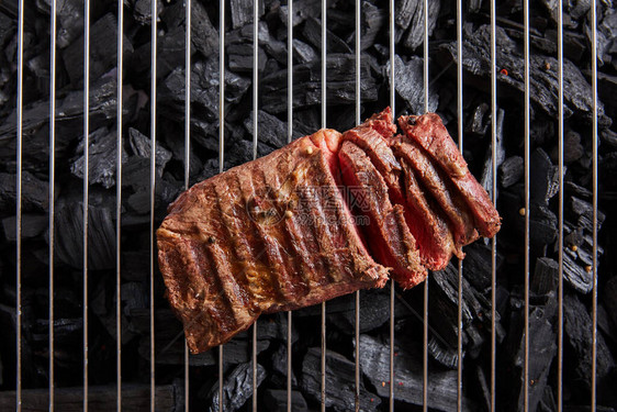 在黑煤上方的格律上烤熟鲜肉牛图片