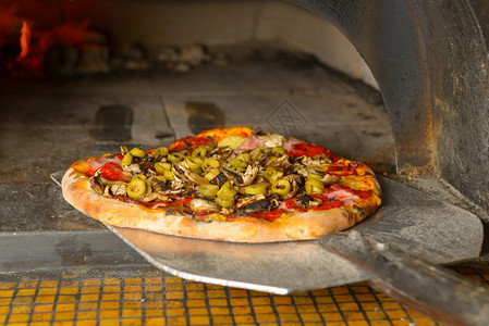 一把铲子上的意大利新披萨正被放进一个传统的烧图片