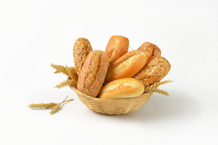 白色背景上一篮子各种面包卷和小圆面包图片