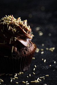 甜巧克力蛋糕的近视和黑色上喷洒的糖图片