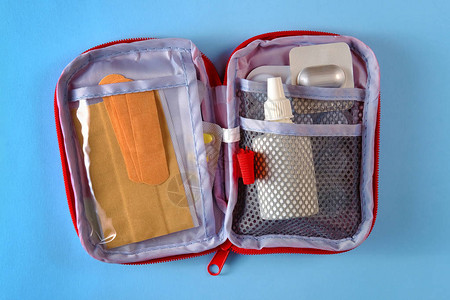 内装有药丸粘胶绷带和鼻涕喷雾的红色旅游急救包袋打开图片