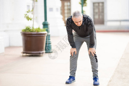 灰色头发的男人看着疲倦从户外奔跑用双手跪着图片