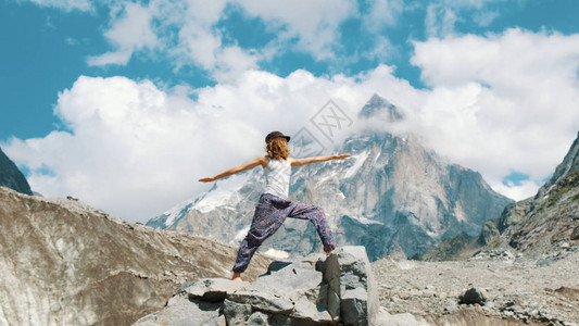 女人在徒步旅行时在雪山背景下进行基本的瑜伽体式女孩在大自然中徒步旅行时在新鲜背景图片