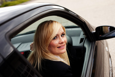 一位微笑着的女司机坐在汽车轮上图片