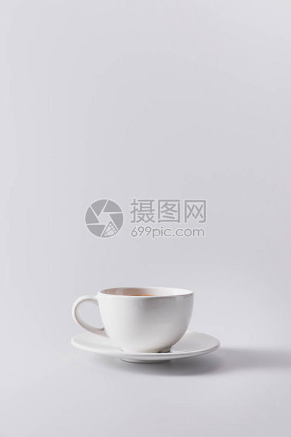 白色杯子在茶碟上加芳香咖啡以灰色隔开图片