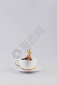 茶盘上从白杯子上喷出的咖啡与灰色隔绝图片