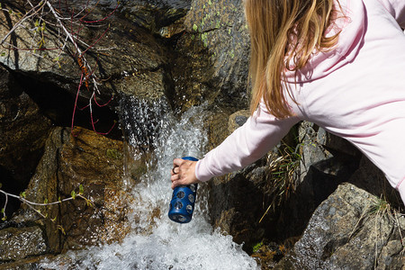 年轻女子将天然泉水灌满瓶装在瓶子图片