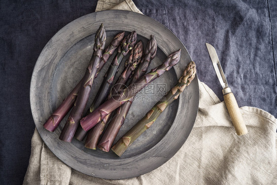 古老的围巾板上新鲜的紫色和旧的皮刀在深色亚麻图片