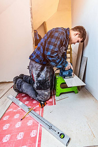 使用电动拼图安装复合地板和切割面板的工人家居装图片