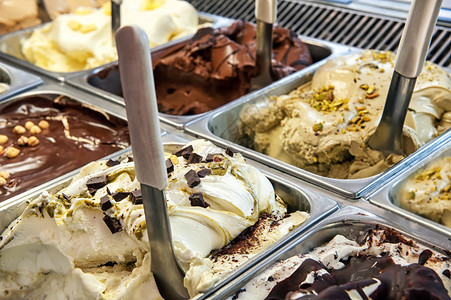 商店橱窗里陈列着各种口味的不同冰淇淋托盘的特写图片