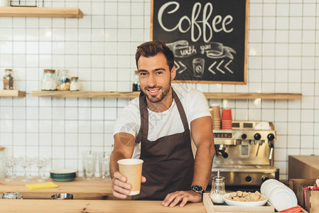 微笑的咖啡师把咖啡放在咖啡厅图片
