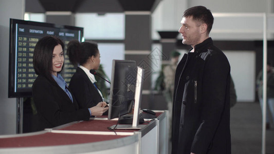 两名女机场保安人员在出发航站楼的值机柜台或登机柜台检查身份图片