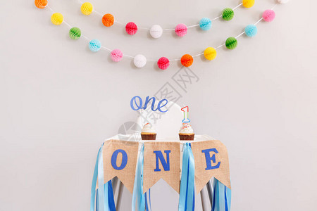 生日庆祝的节日背景装饰字母在婴儿生日的小纸杯蛋糕中发短信给一根蜡烛背景上的花环装饰蛋背景图片