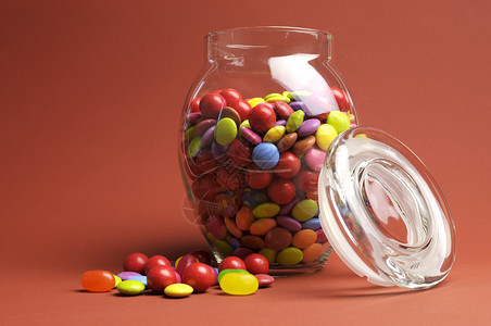 GlassJar满是明亮多彩的宝盒和糖果盖着红橙色的背景上面有你文图片