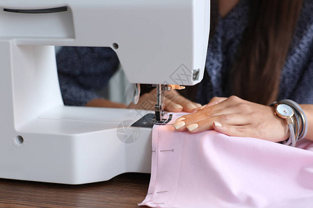 使用缝纫机的年轻女裁缝特写图片