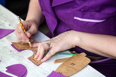 一位身穿紫色制服的女裁缝的特写镜头在桌子上图片