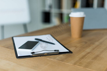智能手机和一次咖啡杯在办公室的木制背景图片