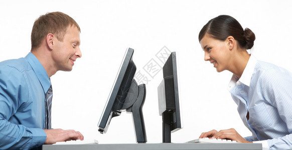 两个业务同事坐在他们的显示器对面图片
