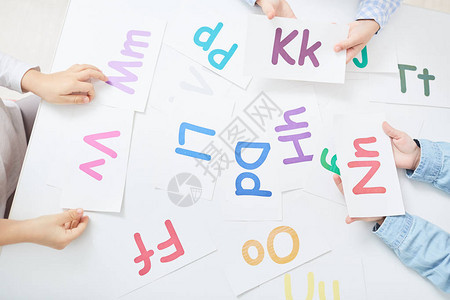 在字母游戏中手持纸牌和彩色字母图片