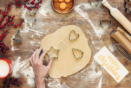制作姜饼干和在桌子上做圣诞快乐记号的人图片