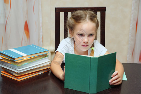 小女孩的侧边视线有胸罩坐在桌子上阅读图片