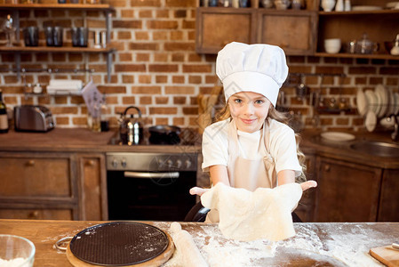 小女孩在厨房的木桌上做披萨面团背景图片