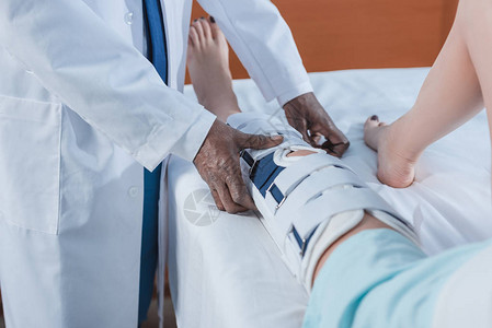 african美国医生在诊所受伤的病人腿上戴脚支图片素材