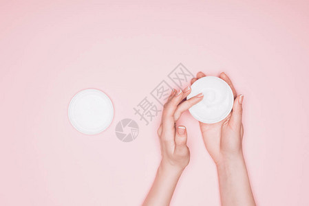 女从粉红色的罐子中取出保湿霜的短片背景图片
