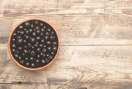 木桌上棕色碗里的黑苦莓图片