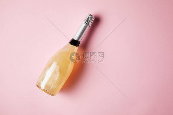 粉红色表面上一瓶香槟的高视图图片