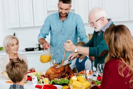 外祖父在庆祝感恩节时在餐桌上切烤火鸡家人一图片