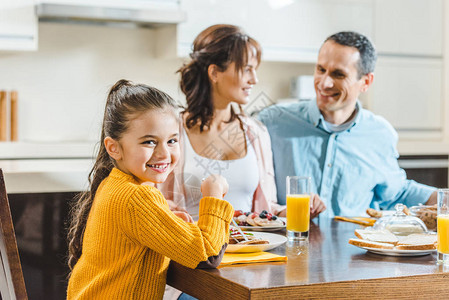 带着煎饼和果汁坐在桌边的幸福家庭小孩图片