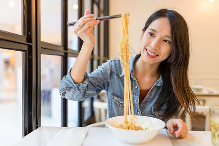 在中餐馆吃面条的亚洲女人图片