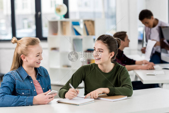 女孩们在课堂上一起学习时互相看对方图片