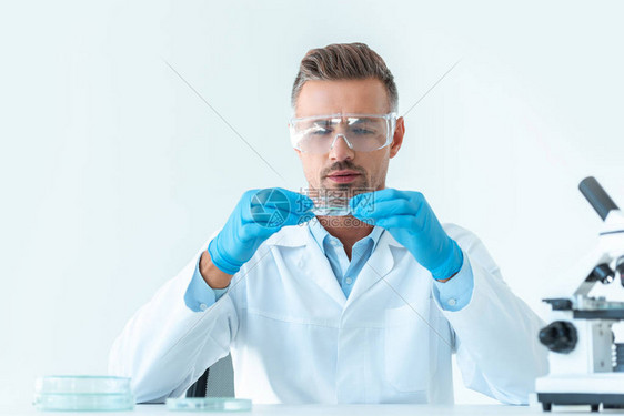 身戴保护眼镜的英俊帅气科学家在孤立于白色的实验图片