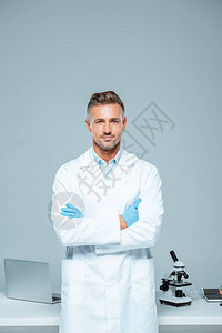 身着白大衣和乳胶手套的英俊帅气科学家站在十字臂上图片