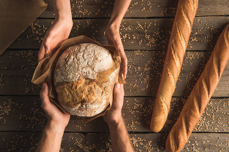 将整块小麦面包和木制桌上新鲜袋式面包放图片