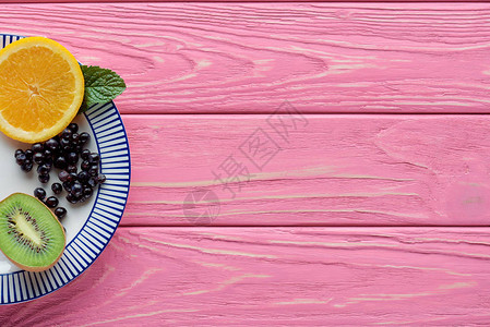粉红色木制桌顶板上盘子上的新鲜成熟水果图片