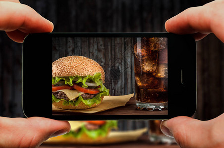 芝士汉堡配上质朴的木桌上的奶酪用智能手机拍摄芝士汉堡的照片过图片