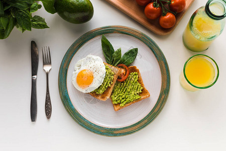 炸鸡蛋和鳄梨饼的顶端用橙汁早餐烤面包用橘子汁图片