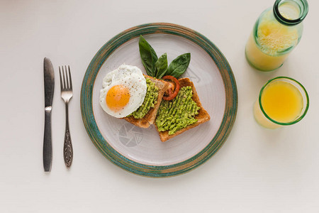 炸鸡蛋和鳄梨饼的顶端风景用橙汁早餐烤面包用橘子汁图片