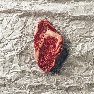 厨房烤纸上生肉牛排的俯视图背景图片