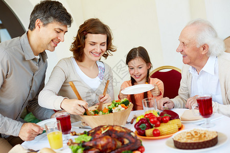 快乐家庭在感恩节晚宴时坐在节日餐桌边的喜图片