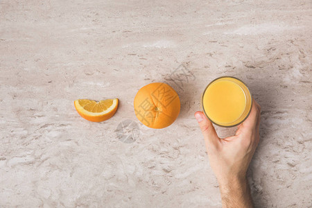 人类从桌子上抽取新鲜橙子汁玻图片