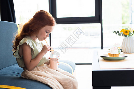 美丽的小红头发女孩坐在咖啡厅喝奶图片