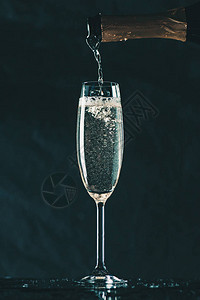 将香槟从瓶子倒在玻璃上放在图片