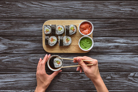持有筷子和吃美味寿司卷的人图片